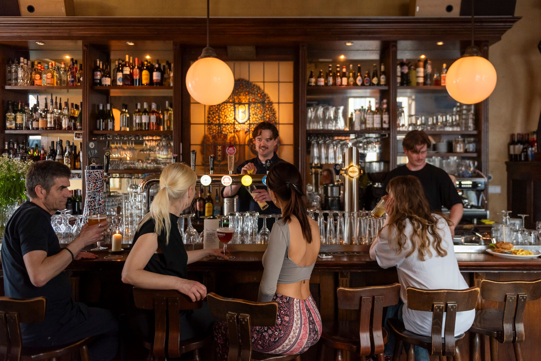 Gasten aan de bar met de bartenders achter de tap