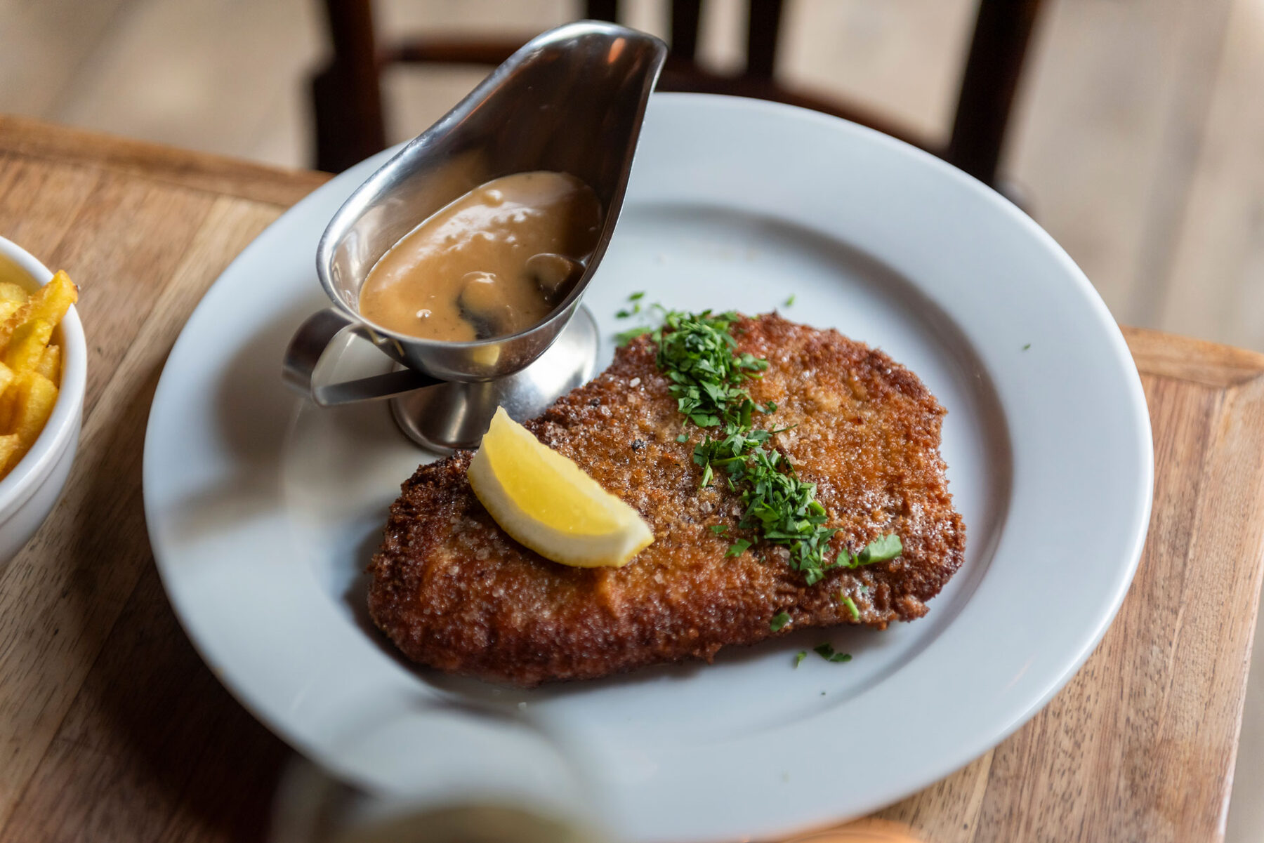 Schnitzel met citroen en sausje op een wit bord